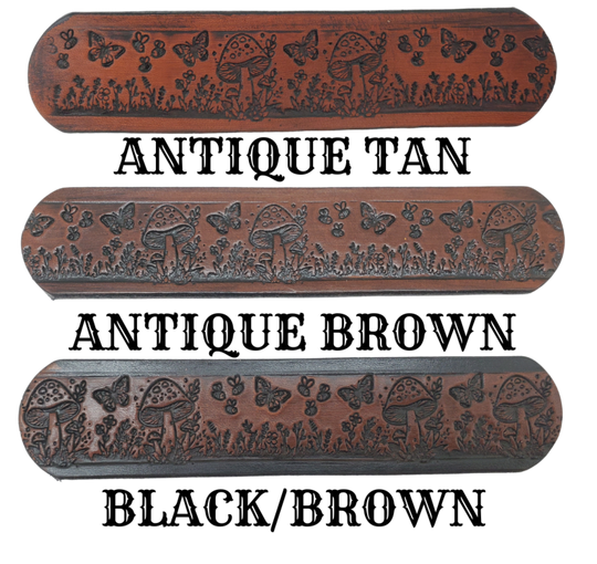 Our 1 1/2" Throwback Groovy Mushroom is a solid strip of USA veg-tan cowhide, embossed with a scene of Mushrooms, Flowers, and Butterflies down length of belt. It is hand finished in&nbsp;3 finishes, with smooth beveled, and painted edges, approx. 1/8" thick. Sizes available are&nbsp;34" to 44" from buckle end to hole most worn.&nbsp; Buckle is an Antique Silver finish brass, held in place with 2 snaps for easy buckle change. Crafted by hand at our Smyrna, Tennessee shop, close to Nashville.