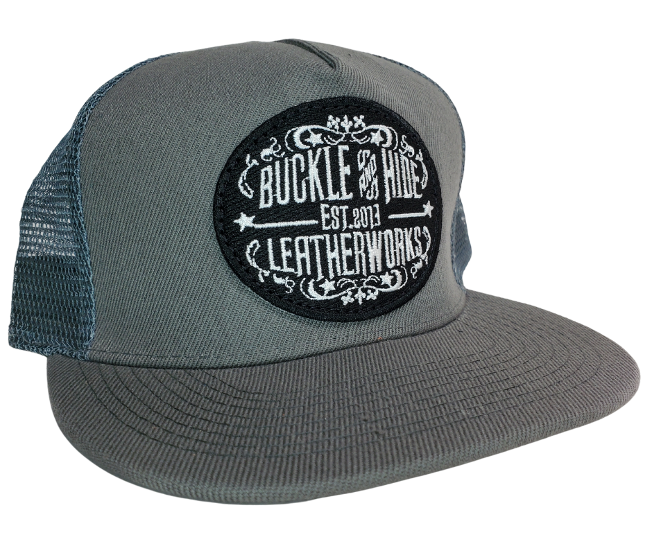 Upgrade your cap game with the Buckle and Hide Classic Flat Bill Trucker Cap, featuring a stylish mesh back, structured top and a snap back. Choose from Black, Grey, Gray/Black or Blk/Gray and proudly wear the Buckle and Hide patch on the front. From your favorite leather shop in Smyrna, TN, just outside of Nashville.