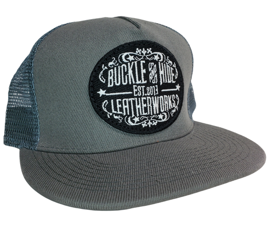 Upgrade your cap game with the Buckle and Hide Classic Flat Bill Trucker Cap, featuring a stylish mesh back, structured top and a snap back. Choose from Black, Grey, Gray/Black or Blk/Gray and proudly wear the Buckle and Hide patch on the front. From your favorite leather shop in Smyrna, TN, just outside of Nashville.