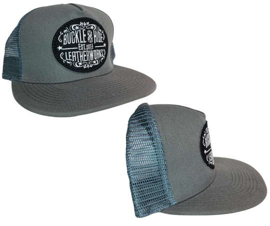 Upgrade your cap game with the Buckle and Hide Classic Flat Bill Trucker Cap, featuring a stylish mesh back, structured top and a snap back. Choose from Black, Grey, Gray/Black or Blk/Gray and proudly wear the Buckle and Hide patch on the front. From your favorite leather shop in Smyrna, TN, just outside of Nashville.