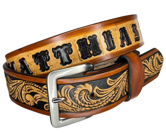 This DELUXE Rustler Name Leather Belt features a classic western Scroll pattern embossed on a 9-10 oz. vegetable-tanned cowhide. You may customize the buckle with the added snaps. It is named Deluxe because of the additional color added to the background of the pattern. This product is crafted with care in our Smyrna, TN shop, just outside Nashville, TN.