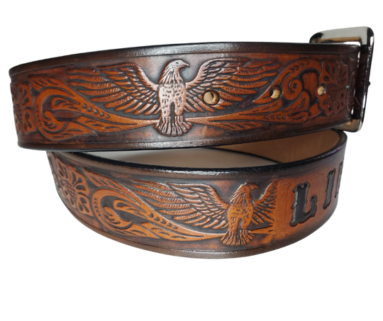 This Name Belt features a single strip of vegetable tanned leather in a patriotic pattern, highlighted by a flying eagle. The antique nickel-finished solid brass buckle is easily replaceable, allowing you to customize the design with your own buckle. It's crafted in our Smyrna, Tennessee shop, near Nashville.