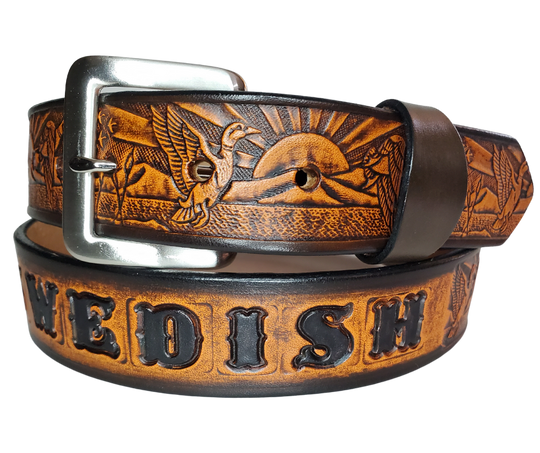 This solid strip of Veg Tan cowhide, is hand stained in 4 brown options, with smooth, finished edges. Embossed with a Mallard Duck scene down length of belt, or have name added to scene up to 8 letters. Belt thickness is approx. 1/8", and 1 1/2" wide. Sizes available are 34" to 44" from buckle end to hole most worn. Attached with 2 snaps is a Brushed Nickel plated solid brass buckle. 