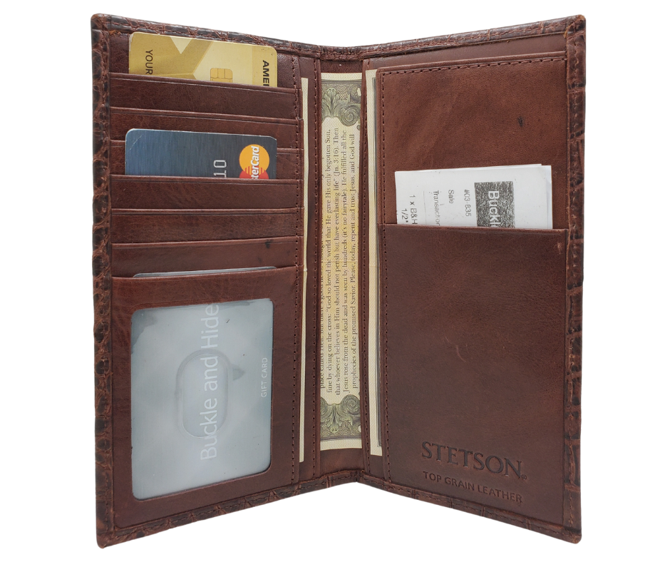 Fully Licensed Stetson Logo Roper/Checkbook style Wallet. Made from Cognac Brown Croc or Black print cowhide leather so good it's really hard to tell the difference from the real thing! Classic Roper design on the inside made from soft durable cowhide leather. Featuring on the left inside 6 card slots and I.D. pocket along 2 underside pockets. On the right inside 1 under pocket with a additional slot on top. In stock at our Smyrna, TN retail store 30 min. from downtown Nashville. Imported.