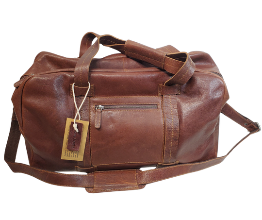 The Traveler Leather Duffel bag is available at our Smyrna, TN shop not far from Nashville. It has a single zip pocket on the side approx. 6.5 x 6.5”. Detachable leather shoulder strap is reinforced with cotton webbing, 2 leather strap handles, one on each side with reinforcement stitching and handle snaps. Spacious inside compartment with a two-way zipper. Inside pockets on each side one zips and the other is open. Lined with sturdy fabric. Bottom of bag has five rounded feet 