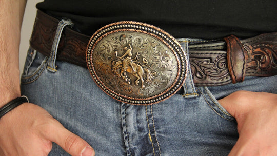 The Montar Bronc buckle has a classic oval shape with a Western scroll design, and a beaded barbwire edge framing a Bronc Rider. This buckle is made from German Silver (nickel and brass alloy) or iron metal base. Some buckles have motifs made of copper, iron or brass and some are adorned with synthetic stones.  Buckle size is Width 4.5” Height 3.5” a little bigger than some of our other buckles that is available in our Smyrna, TN shop.