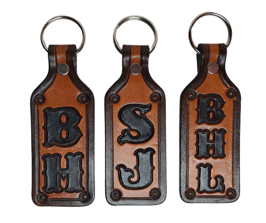 Our Customizable "1973" Medium Leather keychain embossed similar to our popular belts.  Great for identifying luggage, backpacks, or your keys! Available in the below choices All colored in our popular 2 TONE BROWN, pick one or a few. Made in our Smyrna, TN shop. 2 initials will be 1" size, 3 initials will be 3/4" size. Please type desired name in CUSTOM box.  Measures...approx. 1" x 4"