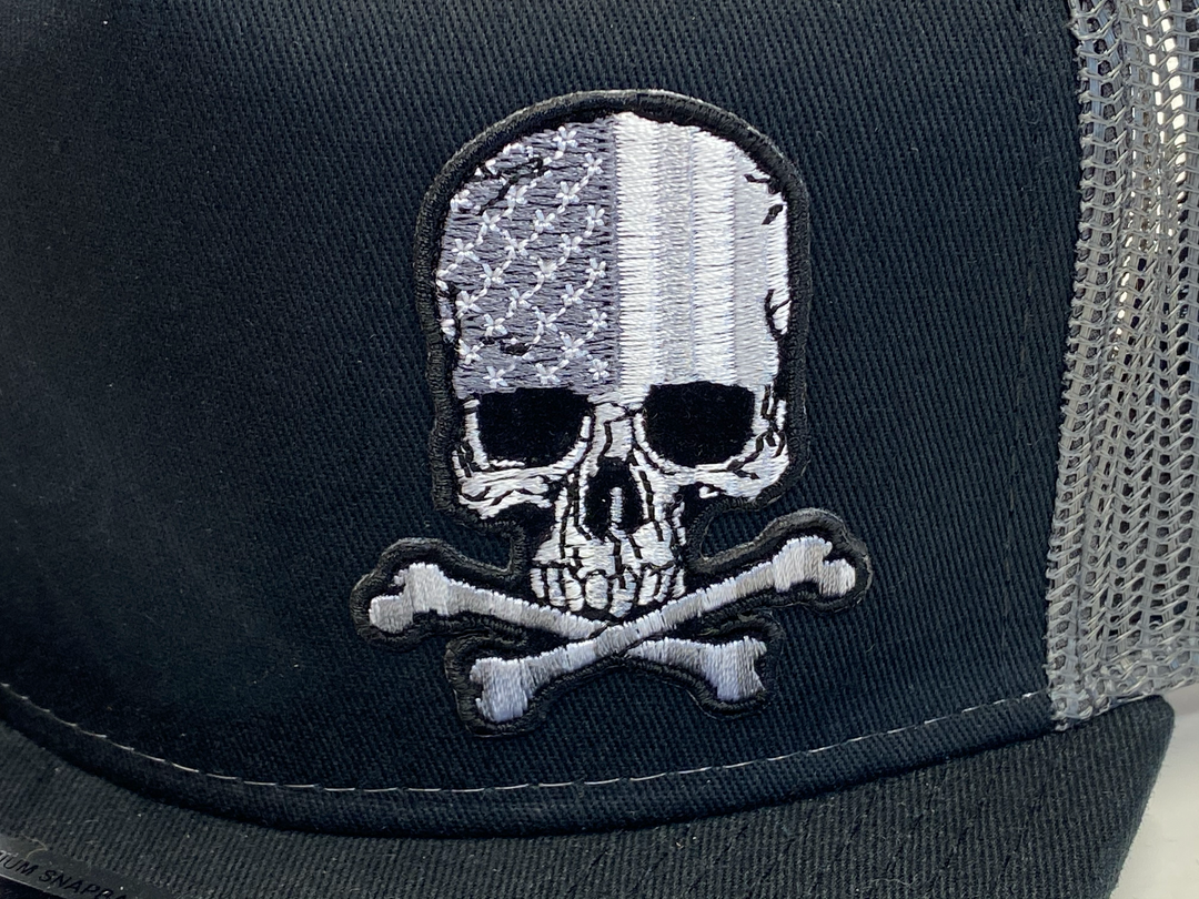 Black Flat Bill Cap with Gray mesh back. Front has a Silver embroidered patch of a skull graphic filled with the American Flag. Structured top to keep its shape. Sold at our shop just outside Nashville in Smyrna, TN.