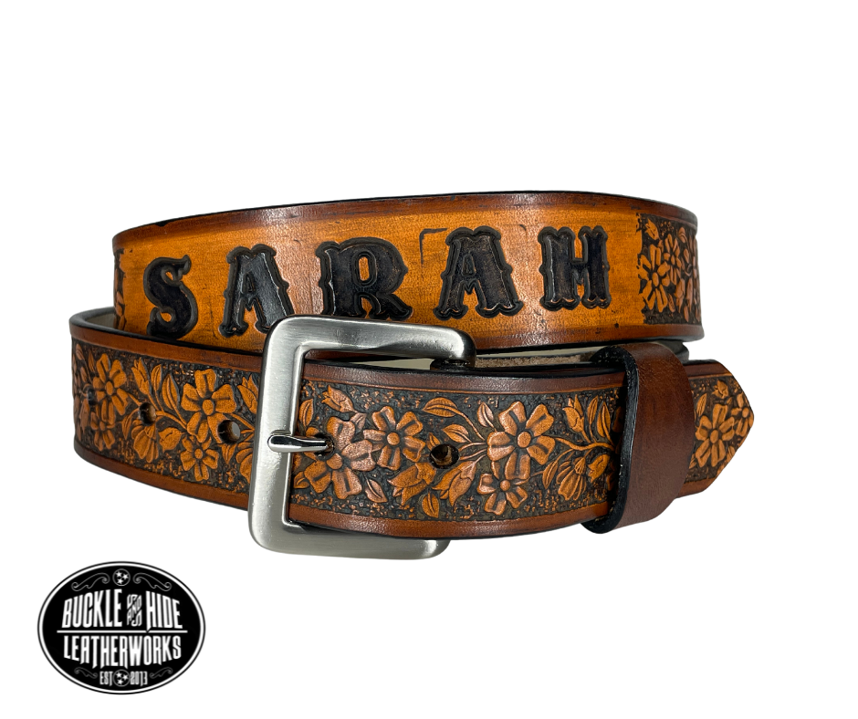 "The Beulah Land" is a handmade real leather belt made from a single strip of cowhide shoulder leather that is 8-10 oz. or approx. 1/8" thick. It has hand burnished (smoothed) edges and summer flowers embossed in 3 color options.  The antique nickel plated solid brass buckle is snapped in place with heavy snaps.  This belt is made just outside Nashville in Smyrna, TN.